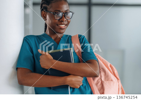 Book and notepads, learning material. Woman student with pink backpack is indoors Book and notepads, learning material. Woman student with pink backpack is indoors 136745254