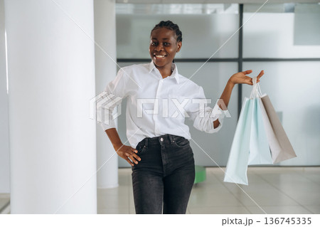 Shopping bags in hands. Businesswoman in formal clothes is in the modern room Shopping bags in hands. Businesswoman in formal clothes is in the modern room 136745335