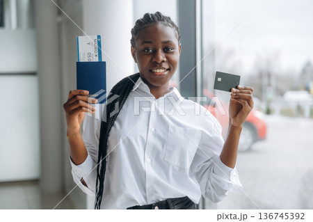 Vacation time, airport, with tickets. Businesswoman in formal clothes is in the modern room Vacation time, airport, with tickets. Businesswoman in formal clothes is in the modern room 136745392