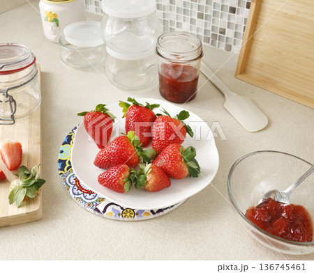Composition of fresh strawberries and empty jars in kitchen. Seasonal farm produce and homemade preserves. Design backdrop. 136745461