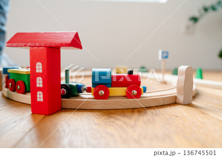 Wooden toy train set on circular track in modern home interior. Educational Montessori-style railway promoting creativity, imagination and fine motor skills development for toddlers and preschool Wooden toy train set on circular track in modern home interior. Educational Montessori-style railway promoting creativity, imagination and fine motor skills development for toddlers and preschool 136745501