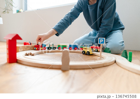 Adult helping child build wooden train track. Montessori-inspired learning activity supporting creativity, problem solving and fine motor skills development 136745508
