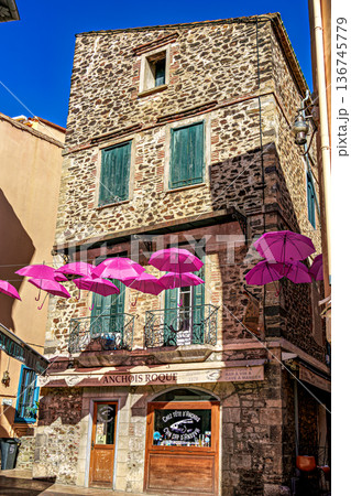 Collioure, France - Nov 03, 2025: Pink umbrellas hanging in the streets of Collioure in France. 136745779