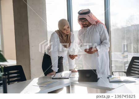 Big project, standing by table. Muslim man and woman are indoors in modern building 136745825