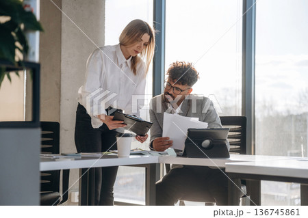Digital tablet and documents. Man and woman are indoors in modern building 136745861
