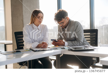 Cooperation, working on project. Man and woman are indoors in modern building 136745877