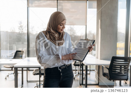 One person, front view. Muslim woman in hijab is in the office One person, front view. Muslim woman in hijab is in the office 136746123