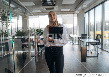 Paperwork, documents in hand. Muslim woman in hijab is in the office Paperwork, documents in hand. Muslim woman in hijab is in the office 136746126