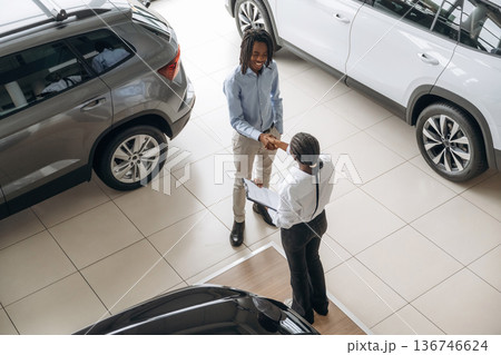 Handshake, successful deal. Car seller is assisting client in the automobile salon Handshake, successful deal. Car seller is assisting client in the automobile salon 136746624