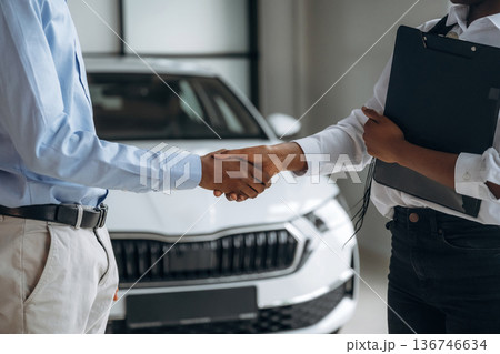 Deal has made, happy new owner. Car seller is assisting client in the automobile salon 136746634
