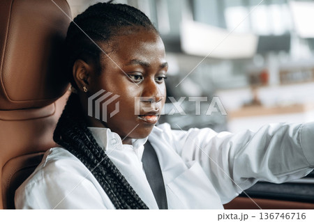 Serious facial expression. Woman in white shirt is in the modern car Serious facial expression. Woman in white shirt is in the modern car 136746716
