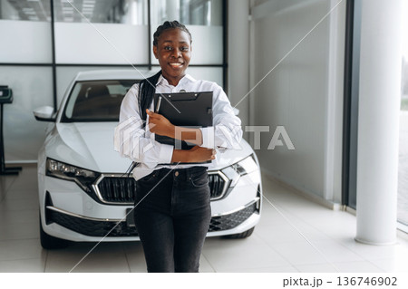 Friendly, smiling. Car seller, businesswoman is standing in automobile salon Friendly, smiling. Car seller, businesswoman is standing in automobile salon 136746902