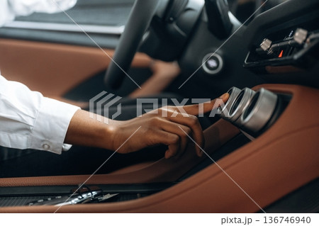 Pressing the button. Woman in white shirt is in the modern car Pressing the button. Woman in white shirt is in the modern car 136746940