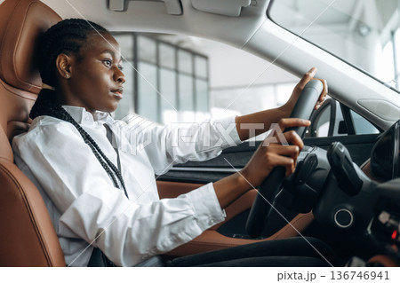 Serious facial expression. Woman in white shirt is in the modern car 136746941