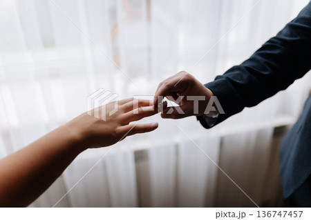 Groom placing wedding ring on brides finger during intimate marriage ceremony moment Groom placing wedding ring on brides finger during intimate marriage ceremony moment 136747457