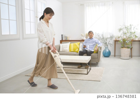 会話をしながら掃除機をかける笑顔の女性と60代の男性 136748381