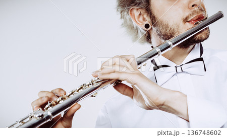Male flutist playing his flute 136748602