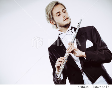 Male flutist wearing tailcoat holds flute 136748617