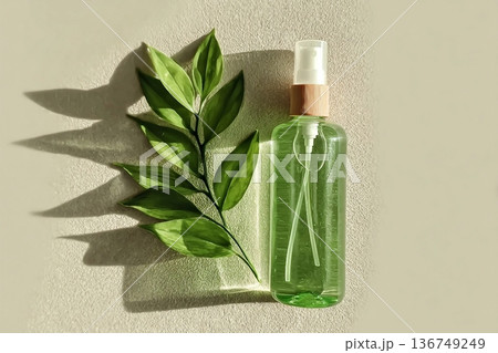 Transparent Cosmetic spray bottle and green leaf, natural light and shadow, dispenser with green liquid on beige. Natural Vegan skin care products, Eco-friendly Organic cosmetics concept, copyspace 136749249