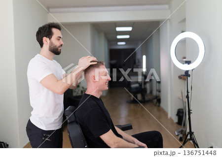 Barber styling male client's hair in modern shop Barber styling male client's hair in modern shop 136751448