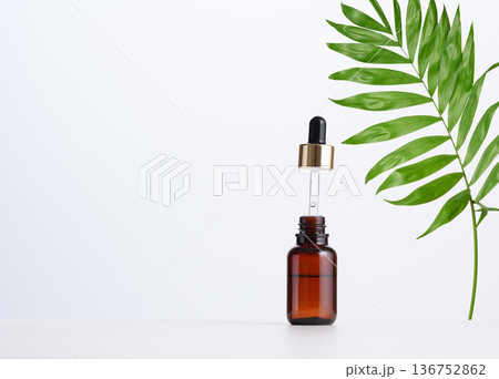Brown glass bottle with a pipette on a white background. Container for cosmetics, oils, serums. Brown glass bottle with a pipette on a white background. Container for cosmetics, oils, serums. 136752862