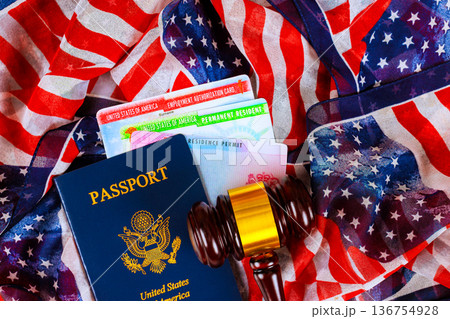 USA passport, residency documents, court gavel are arranged on an American flag in citizenship immigration office space. USA passport, residency documents, court gavel are arranged on an American flag in citizenship immigration office space. 136754928