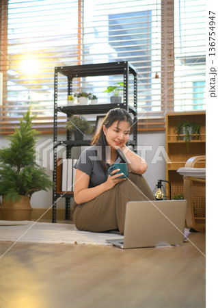 Joyful relaxed woman looking laptop with interest at home Joyful relaxed woman looking laptop with interest at home 136754947