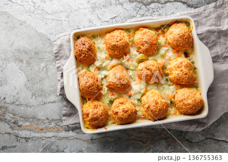 Close-up of chicken casserole with cheese biscuits, vegetables, and chicken soup in a baking dish. Horizontal top view 136755363