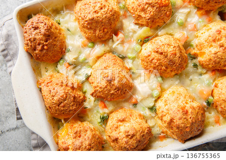 Chicken vegetable soup casserole with biscuits on top close-up in a baking dish. Horizontal top view 136755365
