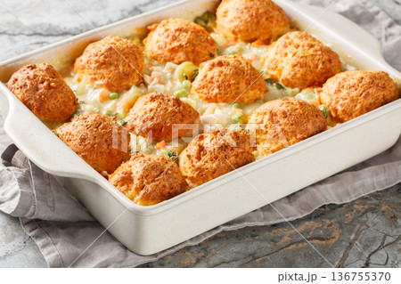 Chicken and biscuit casserole with added vegetables such as onions, carrots, green peas, celery with creamy sauce close-up in a baking dish horizontal Chicken and biscuit casserole with added vegetables such as onions, carrots, green peas, celery with creamy sauce close-up in a baking dish horizontal 136755370