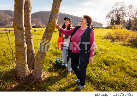 Mature Caucasian woman strolling with granddaughter in green park. Outdoor activity promotes wellbeing and joyful family moments for seniors. Mature Caucasian woman strolling with granddaughter in green park. Outdoor activity promotes wellbeing and joyful family moments for seniors. 136755453