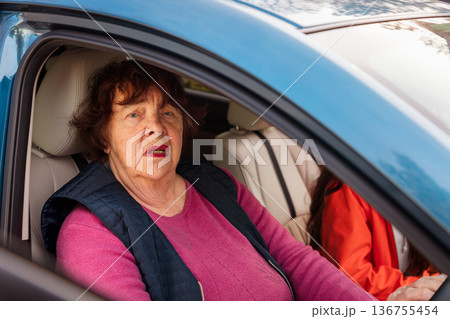 Mature Caucasian woman studies driving with a coach in a modern vehicle. She overcomes fear and gains freedom. Concept of lifelong learning, empowerment, and equality for pensioners. 136755454