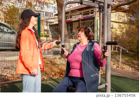 Mature woman trains with a coach in a park after medical treatment. Exercise helps restore endurance, balance, and wellbeing. Mature woman trains with a coach in a park after medical treatment. Exercise helps restore endurance, balance, and wellbeing. 136755456