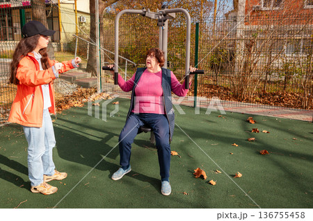 Older Caucasian woman practices fitness in a park as part of recovery after surgery. Exercise improves strength, balance, and long term health. 136755458