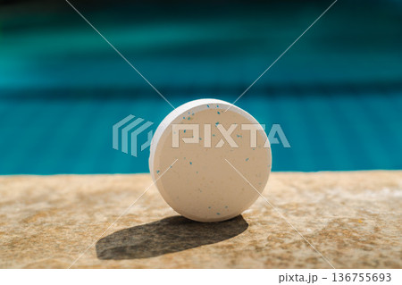 Chlorine tablet on swimming pool edge for water sanitation, pool maintenance, and chemical treatment concept with clear blue background Chlorine tablet on swimming pool edge for water sanitation, pool maintenance, and chemical treatment concept with clear blue background 136755693