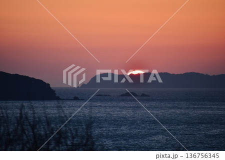 海竜に似た形の岩がある海岸に沈む夕日 136756345