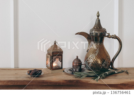 Elegant Iftar dinner. Arabic Coffee Pot, Cup of Tea, Dates and Lantern on Silver Tray. Olive tree branch on wooden table. Ramadan Kareem, Eid Holiday home interior decor. Burning Moroccan lantern. 136756461