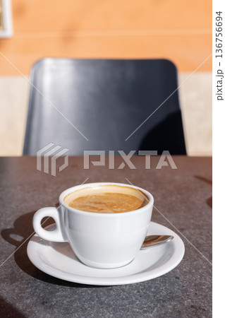 Cup of coffee with milk on a table in a cafe outside. Cup of coffee with milk on a table in a cafe outside. 136756694