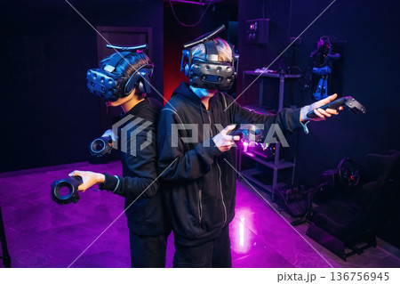 Doing hands gestures. Two young men in virtual reality glasses indoors Doing hands gestures. Two young men in virtual reality glasses indoors 136756945