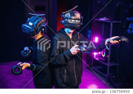 In the dark room. Two young men in virtual reality glasses indoors 136756950