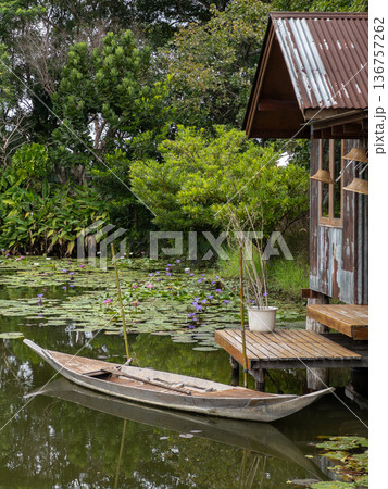 Wooden Rowboat by Rustic Riverside Hut in Lotus Pond. 136757262