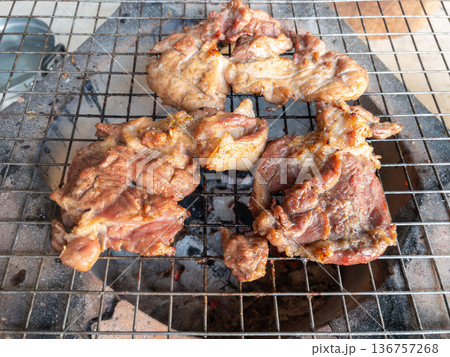 The marinated pork neck meat grilling on a traditional charcoal stove. The marinated pork neck meat grilling on a traditional charcoal stove. 136757268