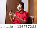 イスに座って笑顔でスマートフォンを操作するシニア女性 画面を見て笑う高齢女性 136757288