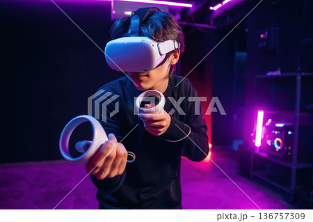Action game experience. Young man is in virtual reality glasses indoors Action game experience. Young man is in virtual reality glasses indoors 136757309