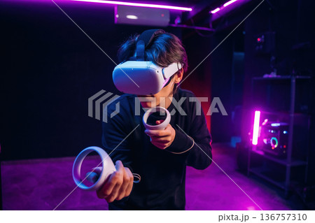 Action game experience. Young man is in virtual reality glasses indoors Action game experience. Young man is in virtual reality glasses indoors 136757310