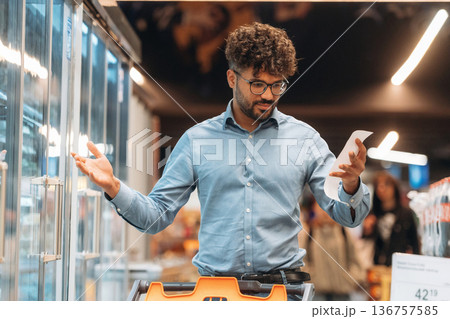 Shopping list in hand. Man is in the grocery store Shopping list in hand. Man is in the grocery store 136757585