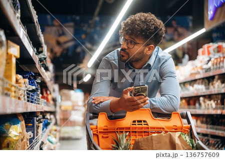 Customer is with phone. Man is in the grocery store 136757609