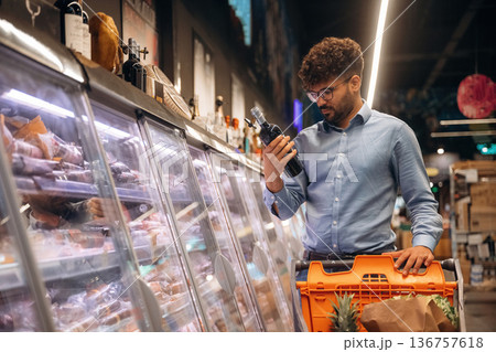 In glasses, choosing products. Man is in the grocery store In glasses, choosing products. Man is in the grocery store 136757618