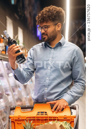 Bottle in hand. Man is in the grocery store Bottle in hand. Man is in the grocery store 136757620