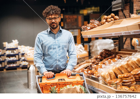 In glasses, choosing products. Man is in the grocery store In glasses, choosing products. Man is in the grocery store 136757642